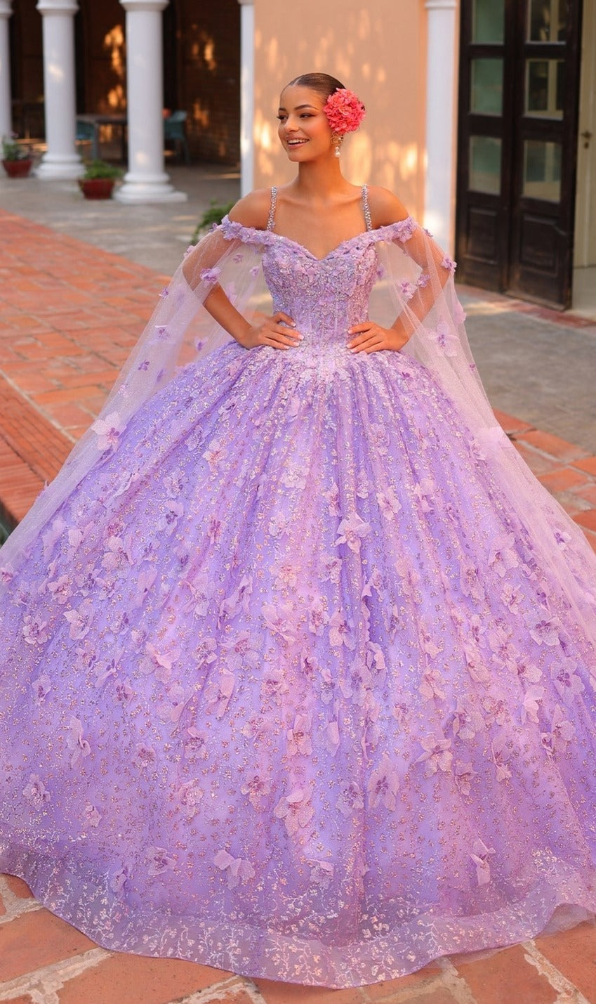A young woman poses outdoors in the Quinceanera Dress 54308 by Amarra, which showcases an off-the-shoulder ball gown design with sheer cape sleeves, 3D floral details, and a pink flower adorning her hair.